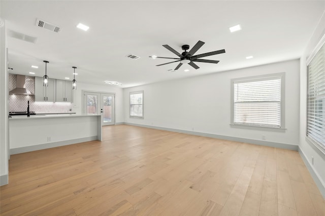 unfurnished living room featuring light wood-type flooring, ceiling fan, and french doors