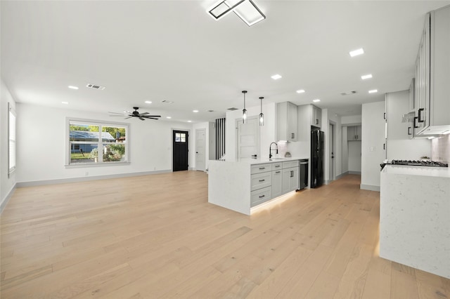 kitchen featuring black refrigerator, white cabinetry, hanging light fixtures, sink, and light hardwood / wood-style flooring