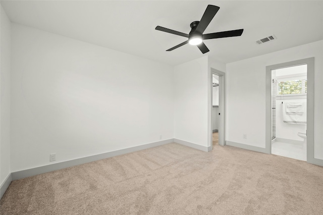 unfurnished bedroom with ceiling fan, light colored carpet, and ensuite bathroom