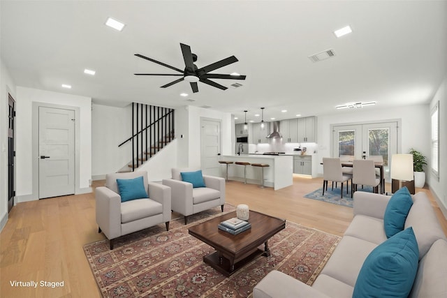 living room featuring ceiling fan, french doors, and light wood-type flooring