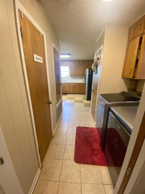 clothes washing area with cabinets, crown molding, separate washer and dryer, a textured ceiling, and light tile patterned floors