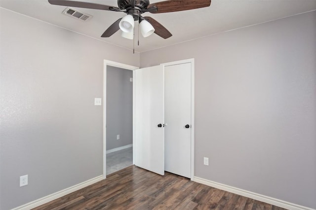 unfurnished bedroom with dark wood-style floors, visible vents, a ceiling fan, a closet, and baseboards