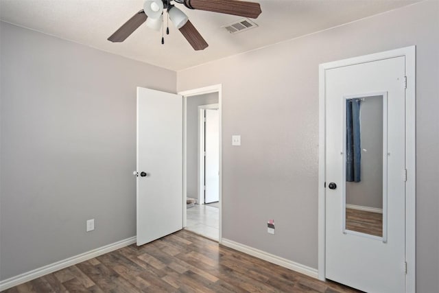unfurnished bedroom featuring ceiling fan, baseboards, wood finished floors, and visible vents