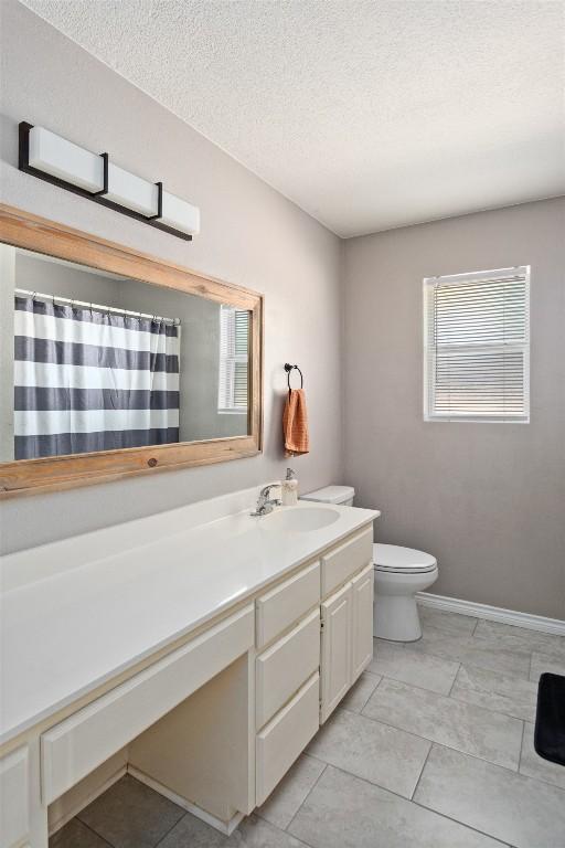bathroom featuring vanity, a wealth of natural light, a textured ceiling, and toilet