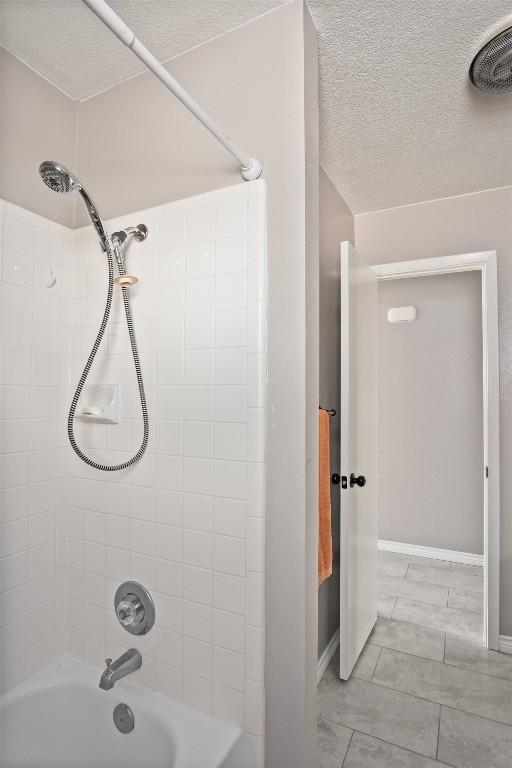 full bath with baseboards, a textured ceiling, and bathing tub / shower combination