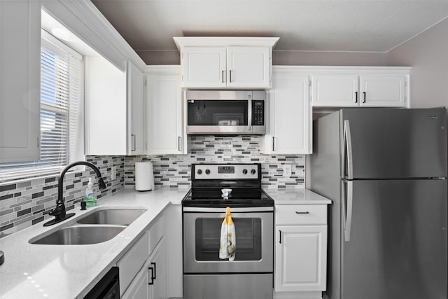 kitchen with white cabinets, backsplash, appliances with stainless steel finishes, and a sink