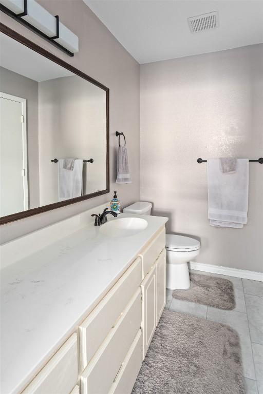 bathroom featuring toilet, vanity, tile patterned floors, and visible vents