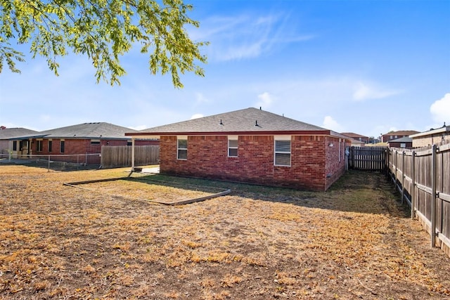 rear view of house featuring a fenced backyard and brick siding
