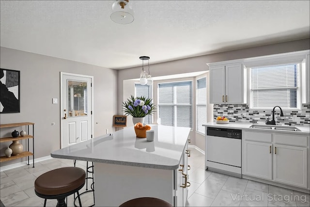 kitchen with dishwashing machine, a sink, a center island, decorative backsplash, and a breakfast bar area