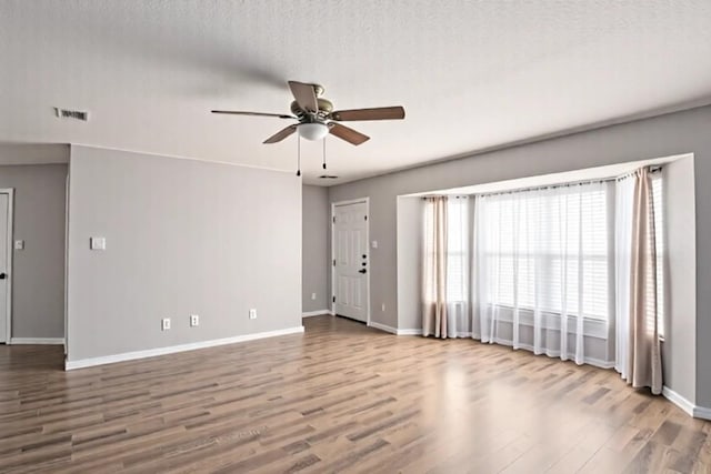unfurnished room featuring wood finished floors, visible vents, baseboards, and ceiling fan