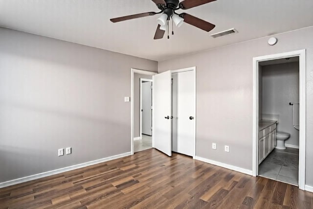 unfurnished bedroom featuring baseboards, visible vents, a closet, ensuite bath, and dark wood-type flooring