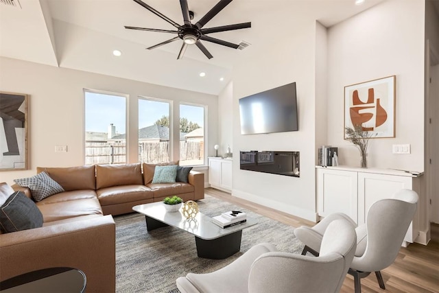 living room featuring ceiling fan, wood-type flooring, and lofted ceiling