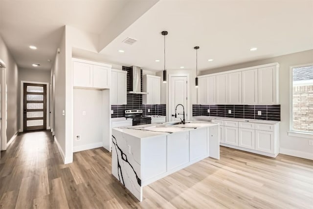 kitchen featuring stainless steel electric stove, white cabinets, and wall chimney range hood