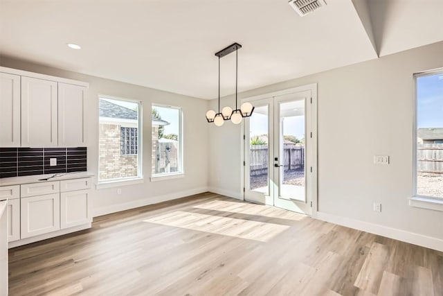 unfurnished dining area with french doors, a healthy amount of sunlight, and light hardwood / wood-style flooring