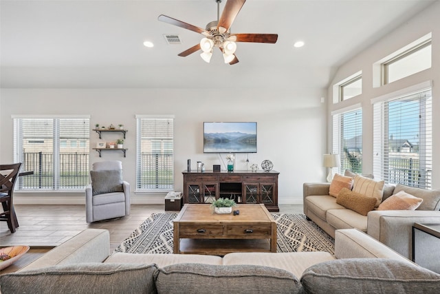 living room featuring ceiling fan, light wood-type flooring, and a wealth of natural light