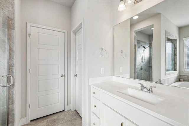 bathroom with a shower with shower door and vanity