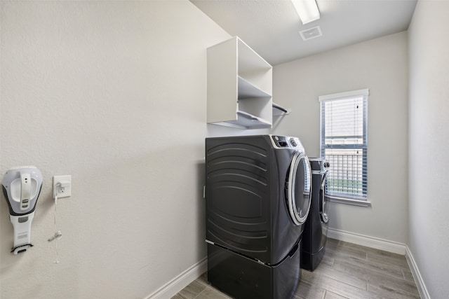 washroom with hardwood / wood-style flooring and washing machine and dryer