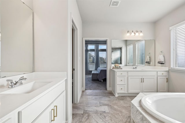 bathroom with vanity, a wealth of natural light, and a relaxing tiled tub