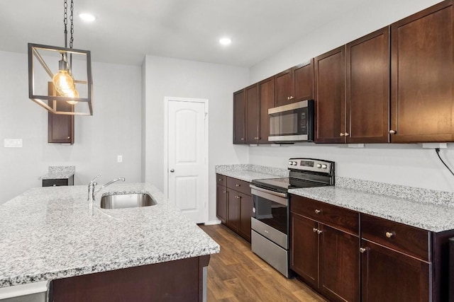 kitchen with pendant lighting, a center island with sink, sink, dark hardwood / wood-style flooring, and stainless steel appliances