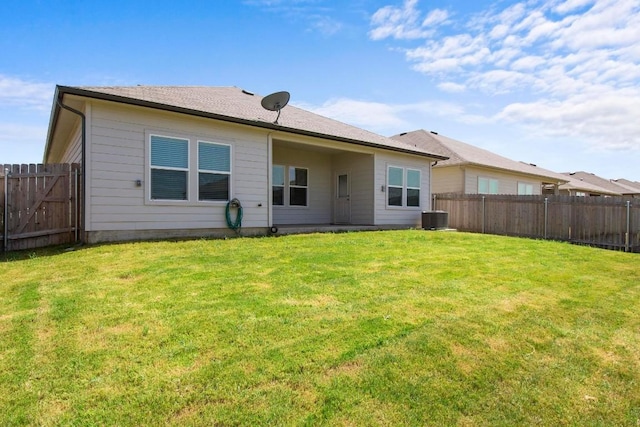 rear view of house with central AC and a lawn