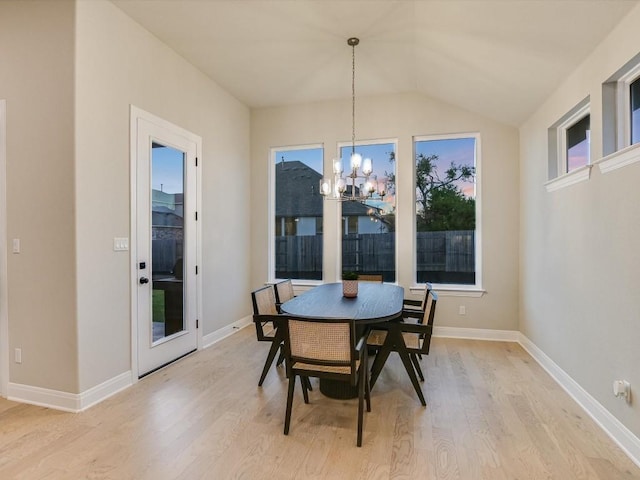 dining area with an inviting chandelier, lofted ceiling, and light hardwood / wood-style flooring