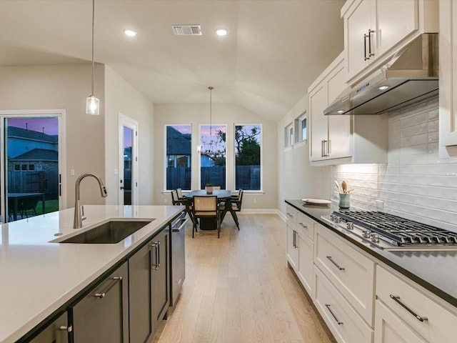 kitchen with pendant lighting, white cabinets, sink, vaulted ceiling, and decorative backsplash