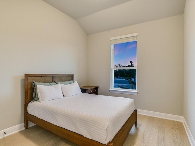 bedroom with vaulted ceiling and light wood-type flooring