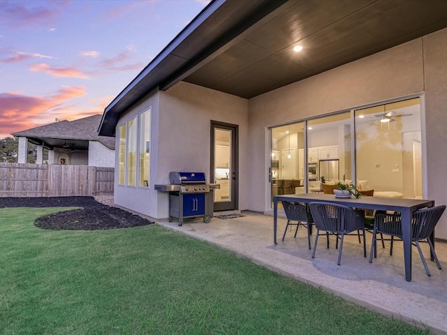 patio terrace at dusk featuring a lawn and grilling area