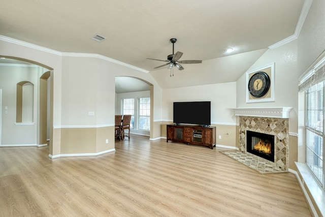 unfurnished living room with a tile fireplace, ceiling fan, light hardwood / wood-style floors, vaulted ceiling, and ornamental molding