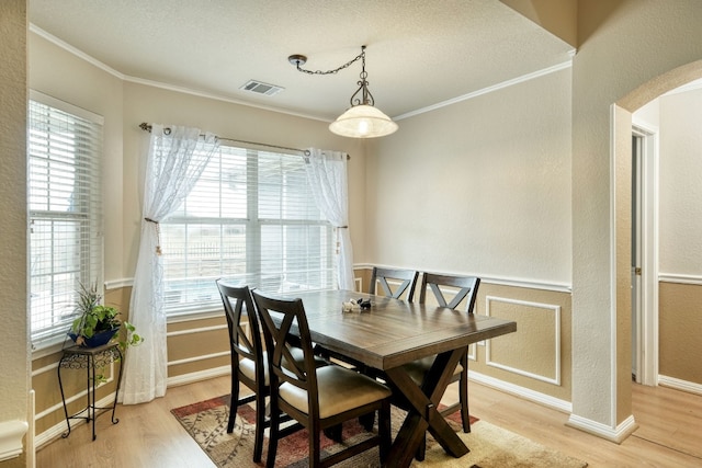 dining area with plenty of natural light, ornamental molding, and light wood-type flooring