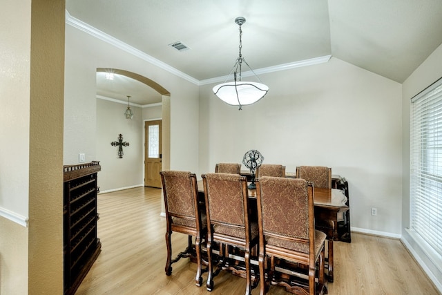 dining room with light wood-type flooring, crown molding, and lofted ceiling