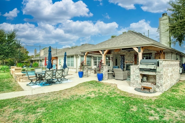 rear view of house featuring a lawn, exterior kitchen, and a patio