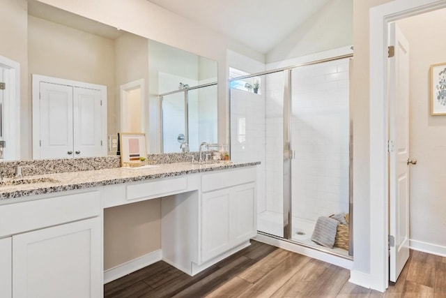 bathroom with hardwood / wood-style floors, vanity, and a shower with shower door