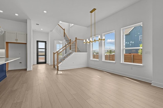 5900 Comanche Moon Trl, Austin, TX 78747 - unfurnished living room with light wood finished floors, stairs, baseboards, recessed lighting, and a chandelier