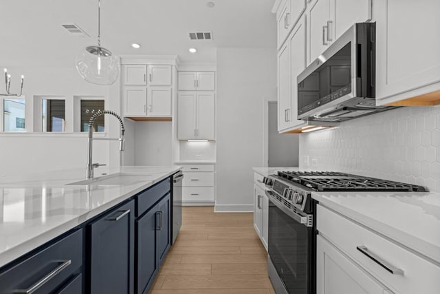505 Terrier Trl, Austin, TX 78745 - kitchen featuring stainless steel appliances, white cabinets, light wood finished floors, tasteful backsplash, and pendant lighting