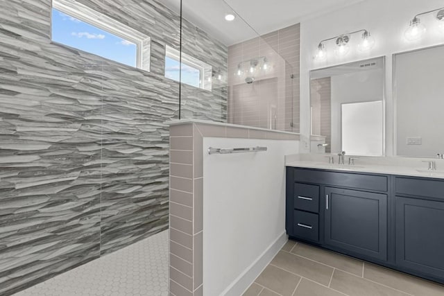 full bath with double vanity, tile patterned flooring, walk in shower, and a sink