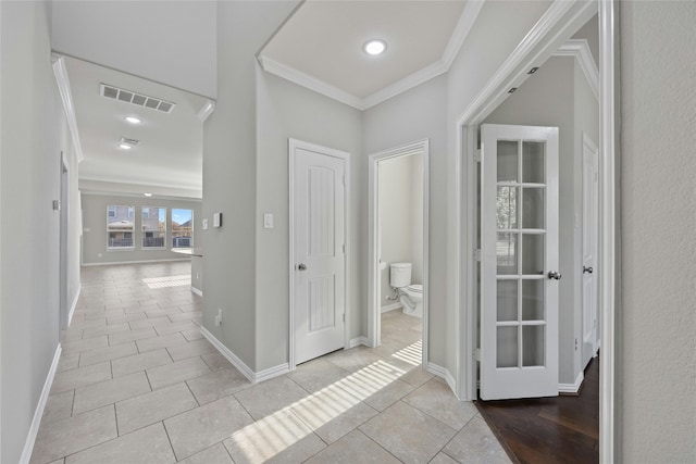 corridor with light tile patterned flooring and ornamental molding