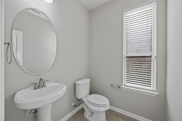 bathroom featuring toilet, tile patterned floors, plenty of natural light, and sink