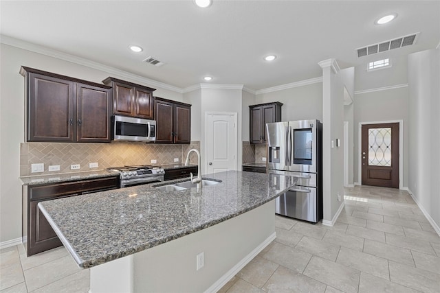 kitchen featuring sink, ornamental molding, an island with sink, dark brown cabinetry, and stainless steel appliances