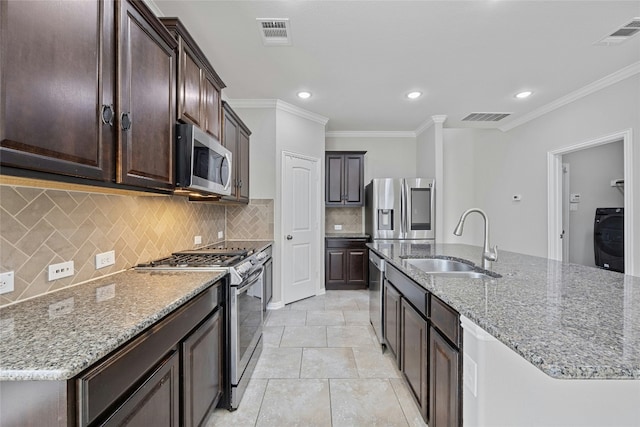 kitchen featuring appliances with stainless steel finishes, a kitchen island with sink, washer / dryer, and sink