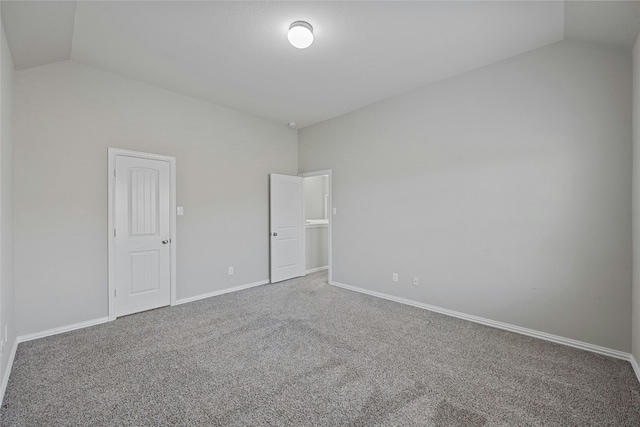 carpeted empty room with vaulted ceiling