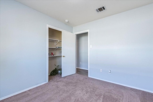 unfurnished bedroom with a closet and light colored carpet