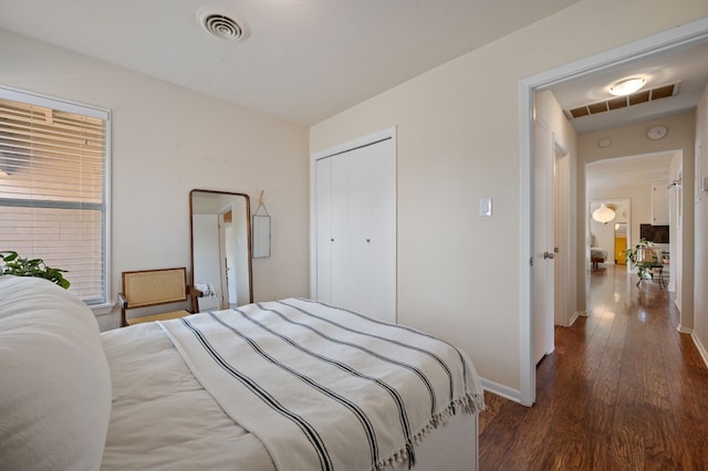 bedroom with dark hardwood / wood-style floors and a closet