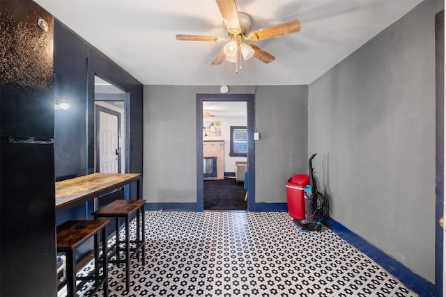 dining space featuring ceiling fan and a fireplace