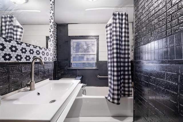 bathroom featuring tasteful backsplash, sink, shower / tub combo, and tile walls