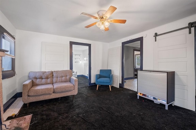 carpeted living room with ceiling fan and a barn door