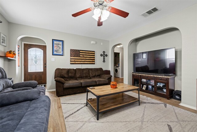 3204 Barksdale Dr, Austin, TX 78725 - living room with arched walkways, washer / clothes dryer, a ceiling fan, wood finished floors, and baseboards