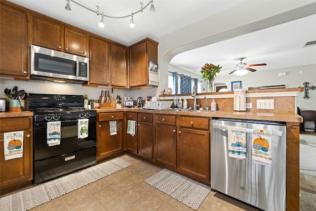 kitchen featuring kitchen peninsula, appliances with stainless steel finishes, ceiling fan, sink, and light tile patterned flooring