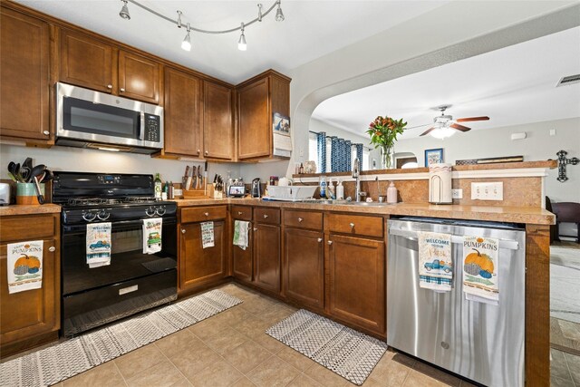 3204 Barksdale Dr, Austin, TX 78725 - kitchen featuring appliances with stainless steel finishes, a peninsula, ceiling fan, arched walkways, and light countertops