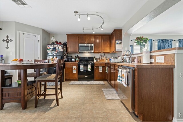 3204 Barksdale Dr, Austin, TX 78725 - kitchen with appliances with stainless steel finishes, a sink, a peninsula, and brown cabinets
